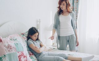 Mother scolds her daughter, who is sitting on the bed.
