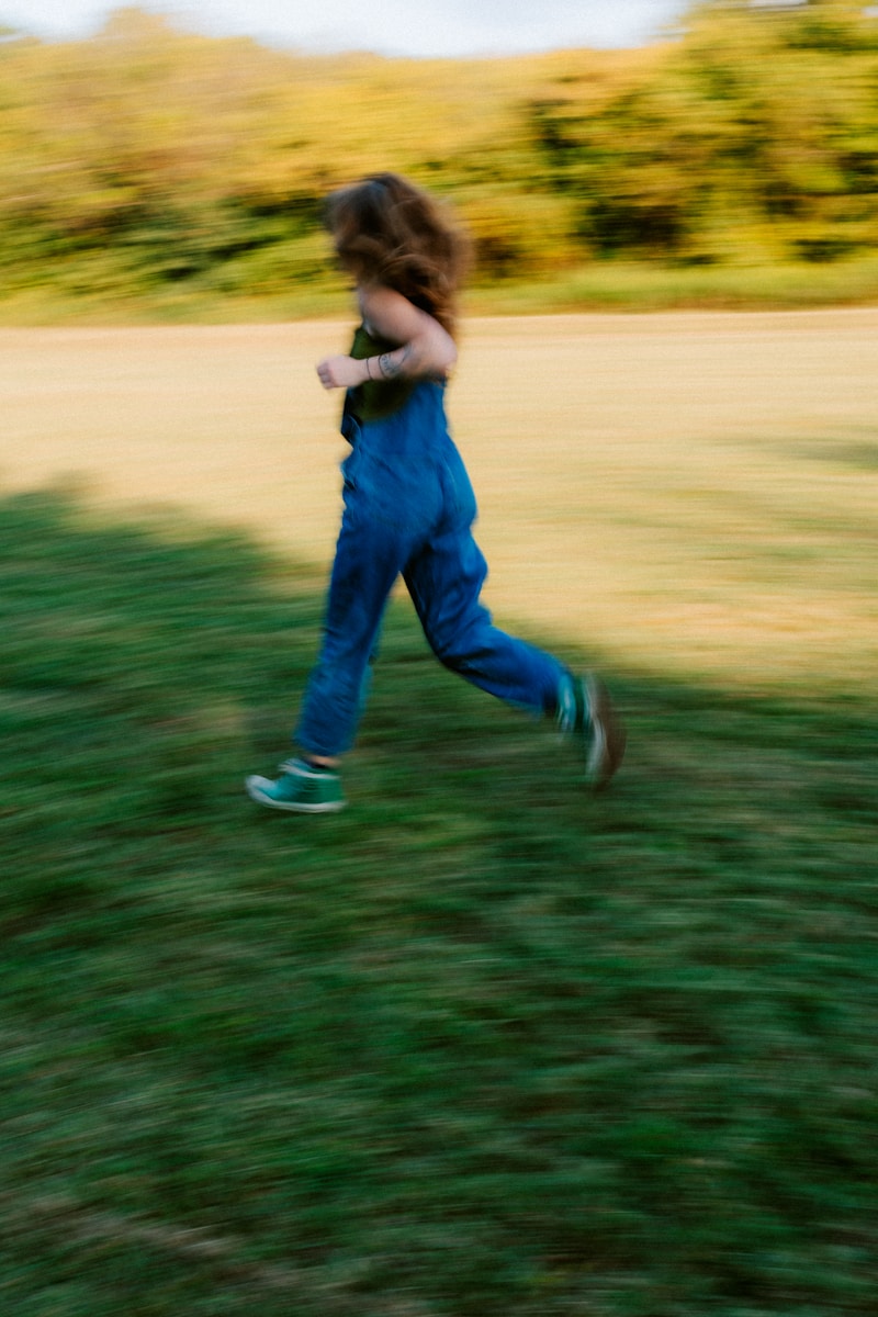 A blurry figure runs through a grassy field.